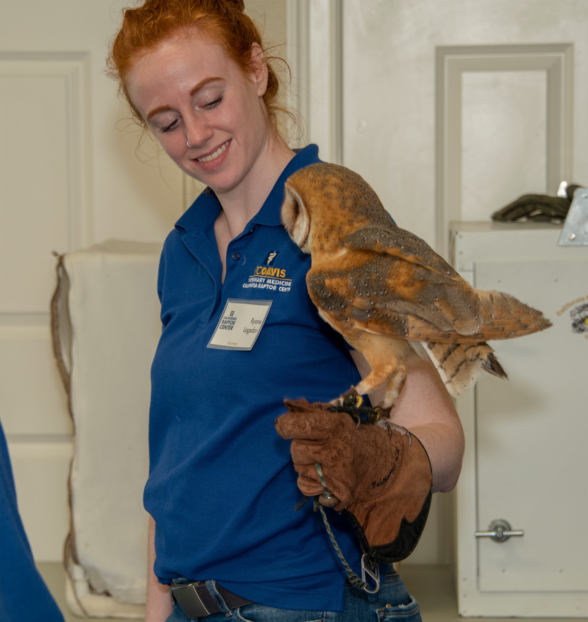 Ryane Logsdon, a volunteer with the Raptor Center, holds Ember, a barn owl, one of the center's resident birds. As part of the Earth Day event, participants were educated on raptor biology, rehabilitation, conservation and species identification during the CRC visit. (U.S. Air Force photo by Heide Couch)