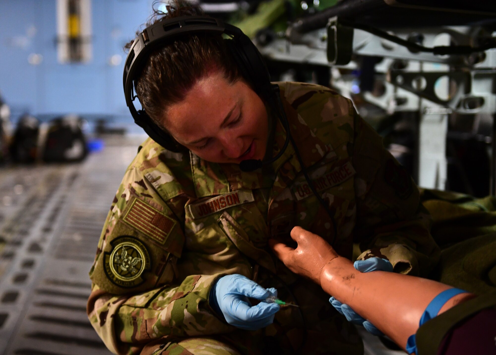 Tech Sgt. Mindy Johnson, 911th Aeromedical Evacuation Squadron medical technician, prepares to insert a needle near Honolulu, Hawaii April 26, 2019. The training in the air was meant to supplement the ground training that they did in Honolulu, Hawaii.(U.S. Air Force Photo by Senior Airman Grace Thomson)