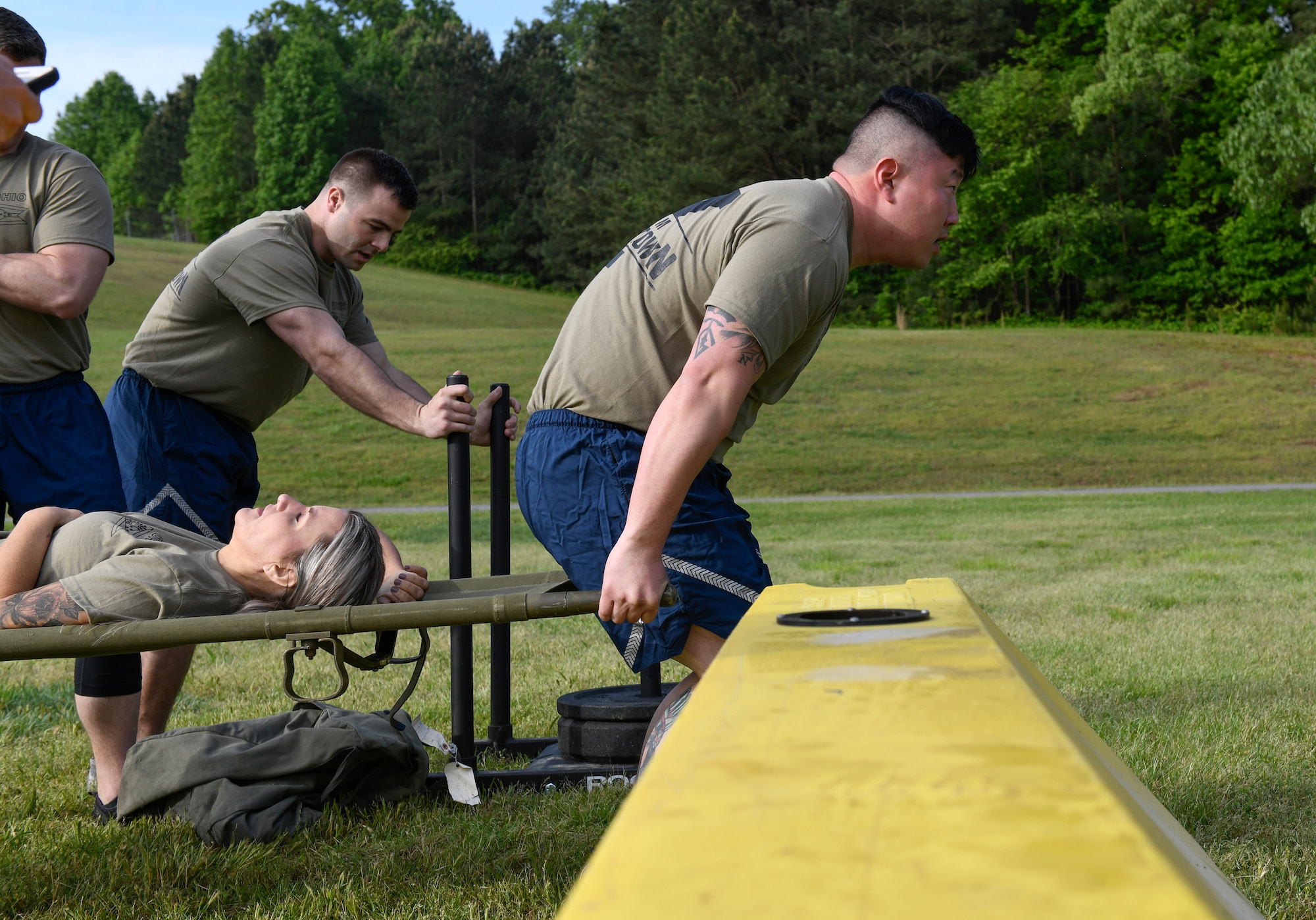 Master Sgt. Tae Choe, a ramp services supervisor assigned to the 76th Aerial Port Squadron, and Tech Sgt. Kyle Peirson, ramp services flight supervisor assigned to the 76th Aerial Port Squadron, carry Tech Sgt. Rebekah Sines, special handling section supervisor assigned to the 76th Aerial Port Squadron, during the fitness competition at the Port Dawg Challenge April 24, 2019, at Dobbins Air Reserve Base, Georgia.