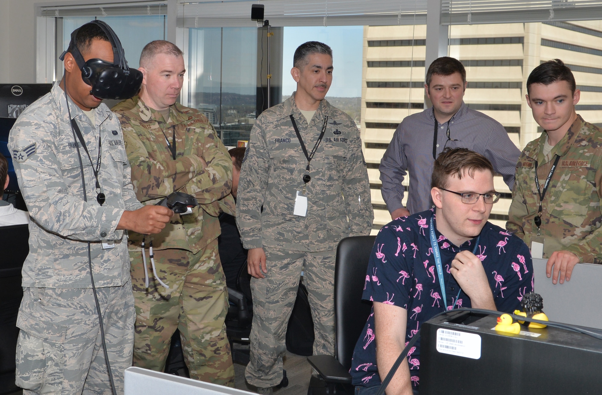 Senior Airman Christopher Orange, 55th Communications Squadron cable maintenance, tests virtual reality (VR) features April 19, 2019, at Booz Allen Hamilton in Omaha, Nebraska. Tyler Vescth, game technician, shows members of 55th Communication Group his interactions on a VR screen. (U.S. Air Force photo by D.P. Heard)