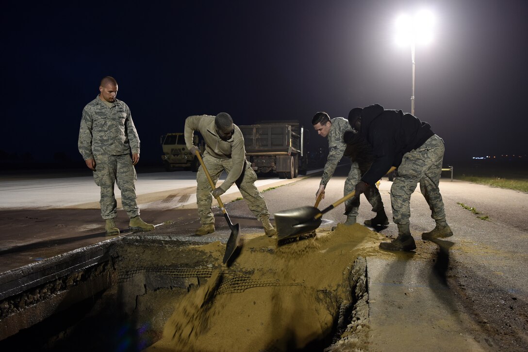 U.S. Air Force 8th Civil Engineer Squadron members shovel dirt into a hole on the flight line at Kunsan Air Base, Republic of Korea, May 1, 2019. 8th CES and 8th Logistics Readiness Squadron worked through the night to get the flight line operational again after it was closed unexpectedly due to a rupture. (U.S. Air Force photo by Staff Sgt. Joshua Edwards