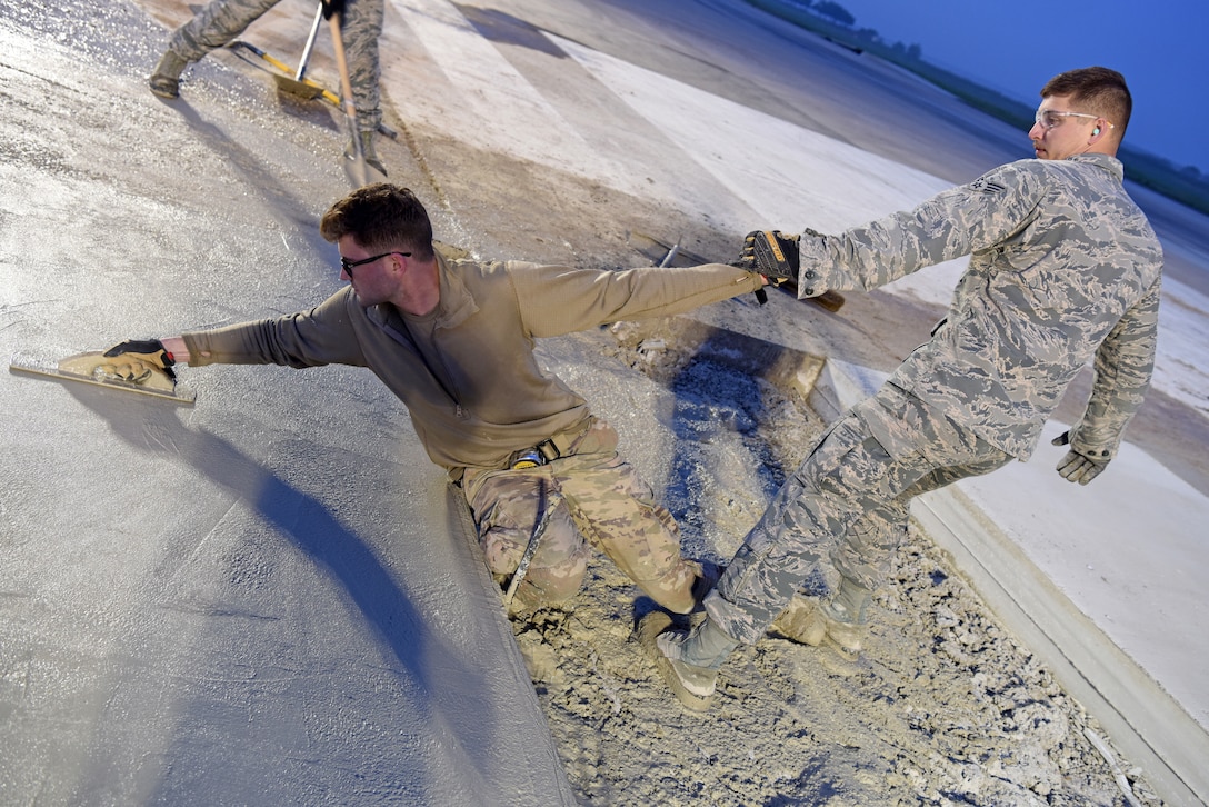 (Right) U.S. Air Force Senior Airman Steven Uhlbeck, 8th Civil Engineer Squadron pavement and construction equipment journeyman, assists Staff Sgt. Jeffrey Deptula, 8th CES, with smoothing wet concrete on the flight line at Kunsan Air Base, Republic of Korea, May 2, 2019. The 8th CES applied rapid airfield damage repair methods to fix a rupture that caused damage to the flight line. (U.S. Air Force photo by Staff Sgt. Joshua Edwards)