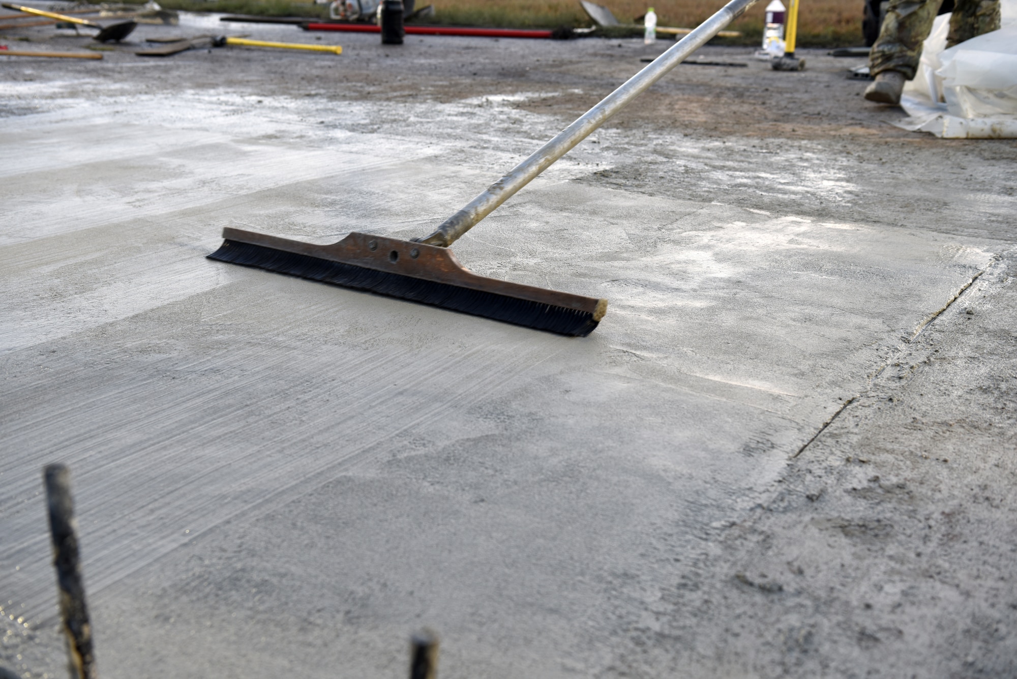 A U.S. Air Force 8th Civil Engineer Squadron member sweeps wet concrete on the flight line at Kunsan Air Base, Republic of Korea, May 2, 2019. The 8th Civil Engineer Squadron and 8th Logistics Readiness Squadron made the flight line operational again just 24 hours after it was shut down to repair a sinkhole. (U.S. Air Force photo by Staff Sgt. Joshua Edwards)