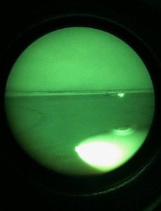 Image from night vision goggles shows hunting party with camp fire, as a Black Hawk helicopter crew from the Alaska Army National Guard arrives to rescue two cold and wet hunters who fell into the Yukon River when their snowmobiles crashed through the nice early May 1, 2019.