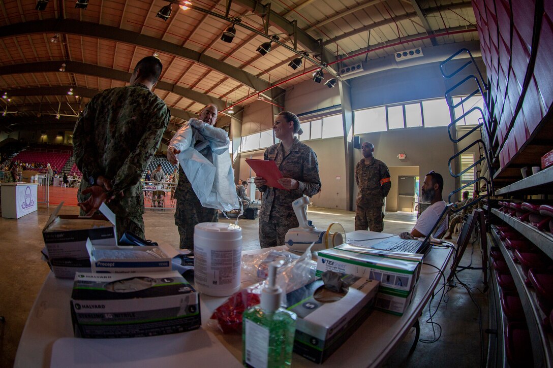 Navy Cmdr. Michael Cabassa, a general dentist with 4th Dental Battalion, 4th Marine Logistics Group, Marine Forces Reserve, puts on a plastic apron at Ponce, Puerto Rico, April 27, 2019, during Innovative Readiness Training Puerto Rico. The purpose of the Innovative Readiness Training Puerto Rico is to provide dental, optometry and medical care to the community while performing joint military humanitarian operations. Marine Forces Reserve is participating in IRT Puerto Rico 2019 in order to maintain military readiness while strengthening alliances with partners. (U.S. Marine Corps photo by Sgt. Andy O. Martinez)