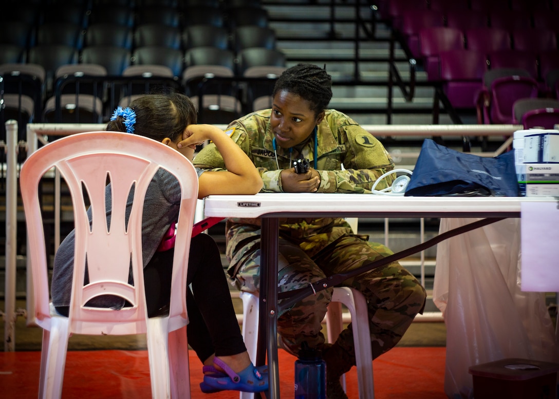 Army Spc. Ashley Jacobs, a health care specialist speaks with a child at Ponce, Puerto Rico, April 27, 2019, during Innovative Readiness Training Puerto Rico. The purpose of the Innovative Readiness Training Puerto Rico is to provide dental, optometry and medical care to the community while performing joint military humanitarian operations. Marine Forces Reserve is participating in IRT Puerto Rico 2019 in order to maintain military readiness while strengthening alliances with partners. (U.S. Marine Corps photo by Sgt. Andy O. Martinez)