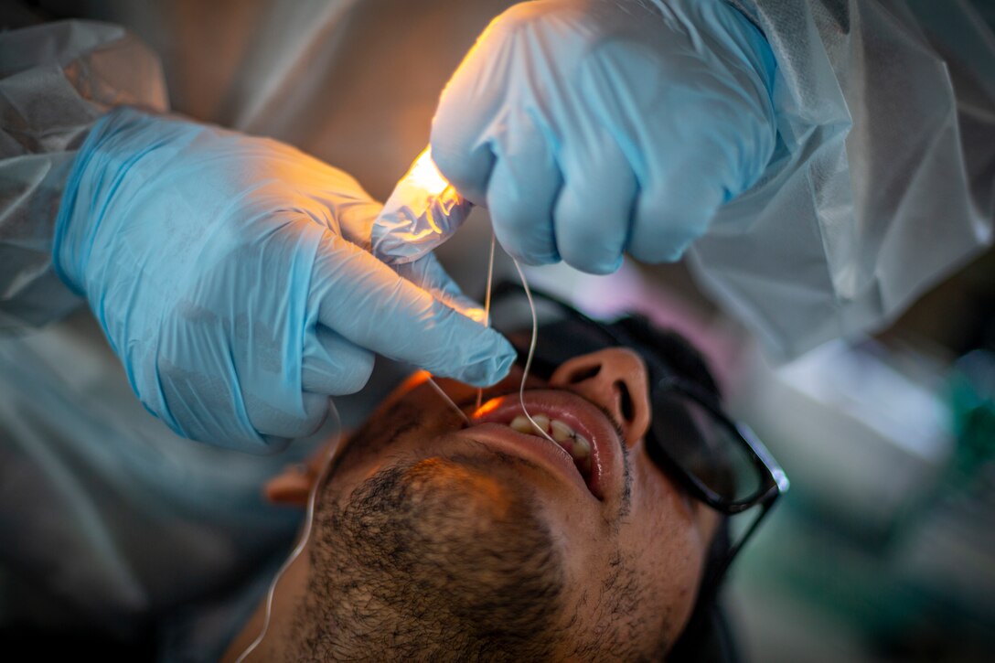 A U.S. Army Solider flosses a patient’s tooth at Yauco, Puerto Rico, April 28, 2019, during Innovative Readiness Training Puerto Rico. IRT Puerto Rico is also called Ola de Esperanza Sanadora, which translates to Healing Wave of Hope. This IRT is part of a civil and joint military program to improve military readiness while simultaneously providing quality services to underserved communities throughout the United States. (U.S. Marine Corps photo by Sgt. Andy O. Martinez)