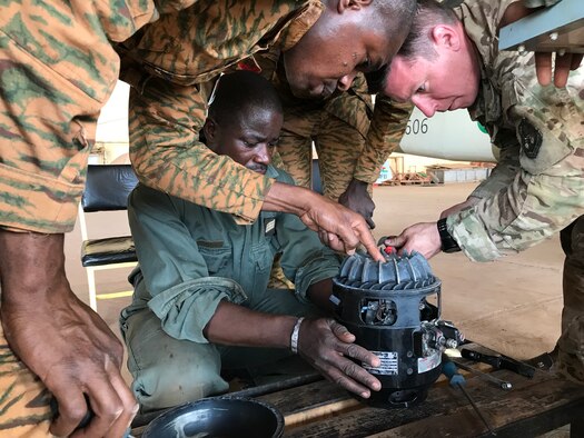 Master Sgt. Russ Asbel, right, 582nd Helicopter Group aircraft maintainer, inspects a main helicopter generator with mechanics from the Burkina Faso Air Force at Airbase 511 in Burkina Faso, Africa, April 10, 2019. Asbel augmented the 818th Mobility Support Advisory Squadron during their building partner capacity engagement to Burkina Faso, Africa, April 5-20. (U.S. Air Force photo by Master Sgt. Sarah Colwell)