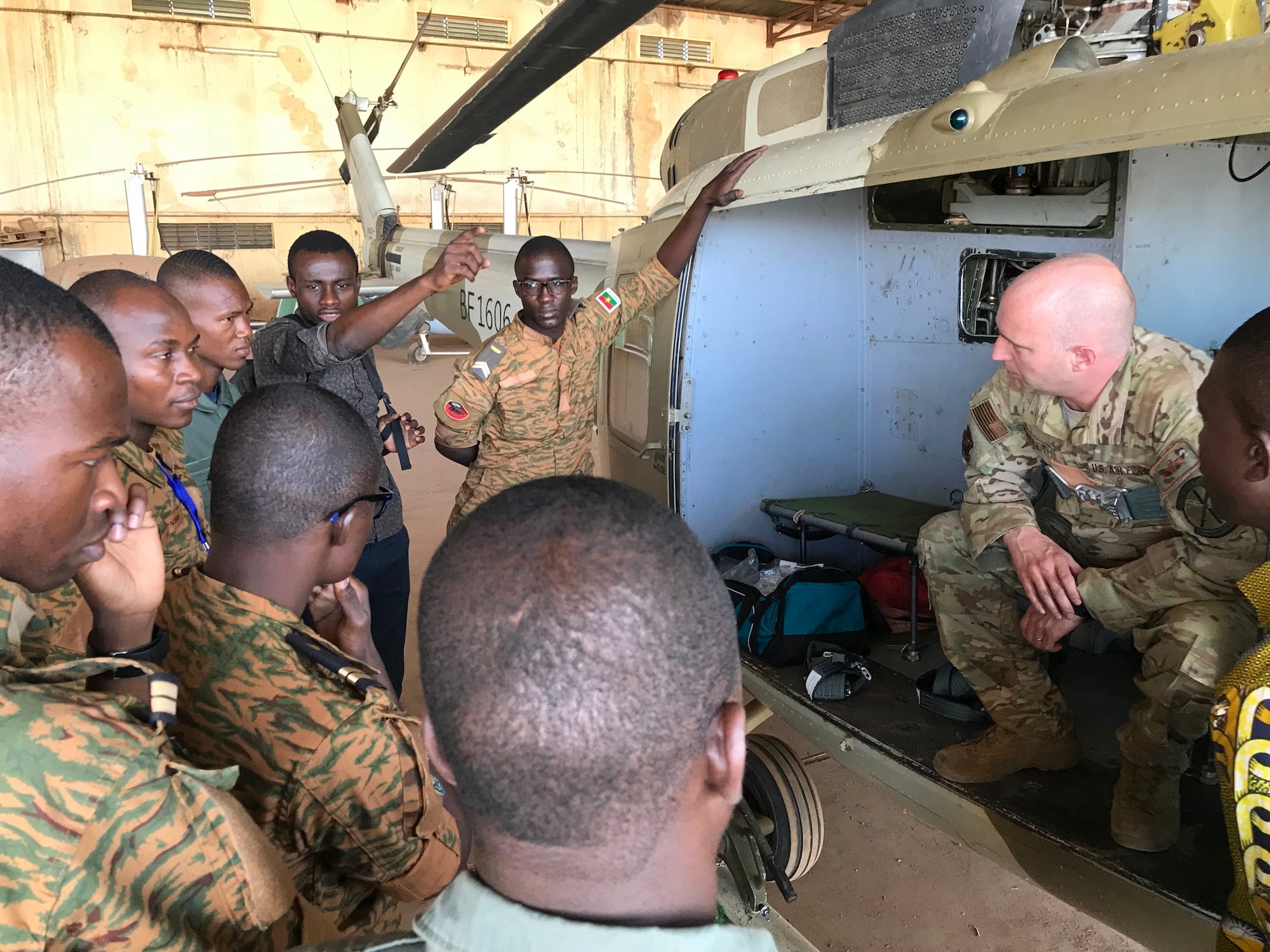 Master Sgt. Todd Chandler, right, 40th Helicopter Squadron flight engineer, leads a small group discussion focusing on aircrew in-flight responsibilities and post flight inspections with flight engineers and mechanics from the Burkina Faso Air Force at Airbase 511 in Burkina Faso, Africa, April 11, 2019.  Chandler augmented the 818th Mobility Support Advisory Squadron during their building partner capacity engagement to Burkina Faso, Africa, April 5-20. (U.S. Air Force photo by Master Sgt. Sarah Colwell)