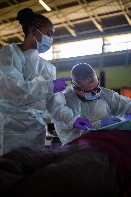 U.S. Navy Petty Officer 3rd Class Carlotta Howard, a dental technician with 4th Dental Battalion, 4th Marine Logistics Group, Marine Forces Reserve (left), and U.S. Navy Lt. Cmdr. Kevin Smith, a general dentist with 4th Dental Bn., 4th MLG, MARFORRES (right), provides dental care to a patient at Yauco, Puerto Rico, April 28, 2019, during Innovative Readiness Training Puerto Rico. IRT Puerto Rico is also called Ola de Esperanza Sanadora, which translates to Healing Wave of Hope. This IRT is part of a civil and joint military program to improve military readiness while simultaneously providing quality services to underserved communities throughout the United States. (U.S. Marine Corps photo by Sgt. Andy O. Martinez)