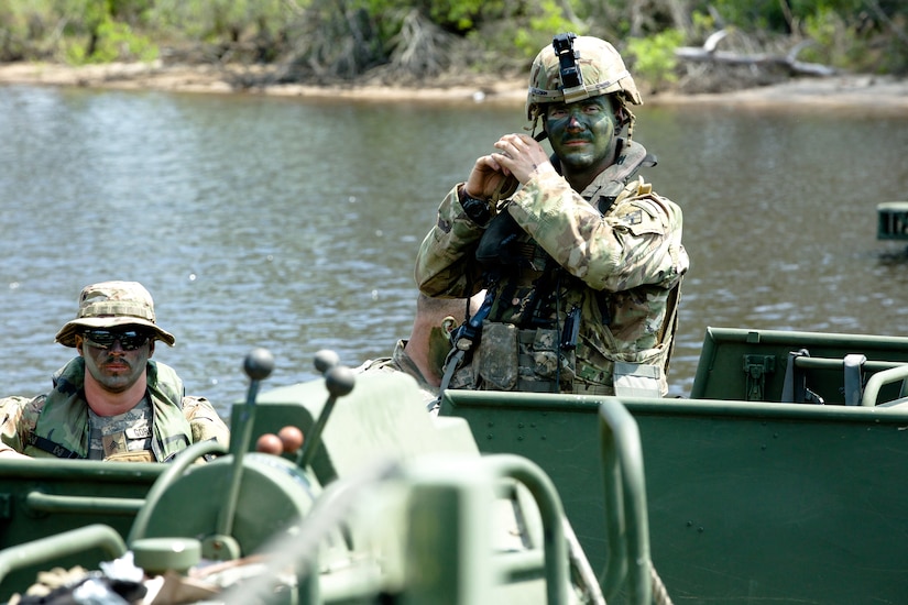 Two soldiers ride in small boat.
