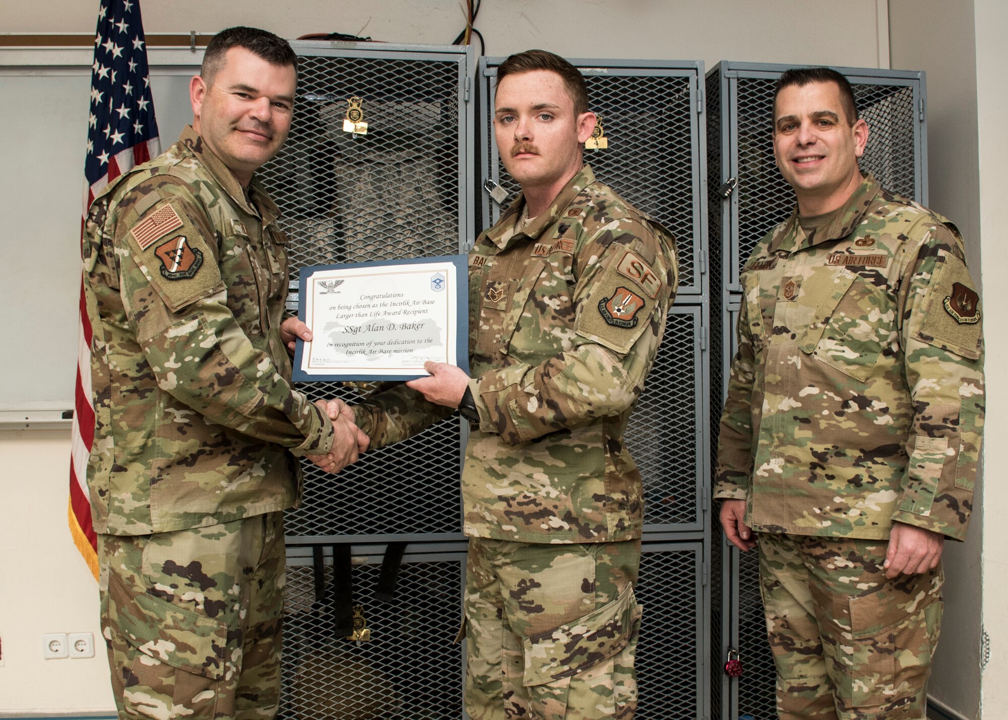 Col. Brian A. Filler, 39th Air Base Wing vice commander, left, and Chief Master Sgt. Jason T. Heilman, 39th ABW command chief, right, present the Larger than Life Award to Staff Sgt. Alan Baker, 39th Security Forces Squadron armory assistant NCO in charge, Apr. 25, 2019, at Incirlik Air Base, Turkey.