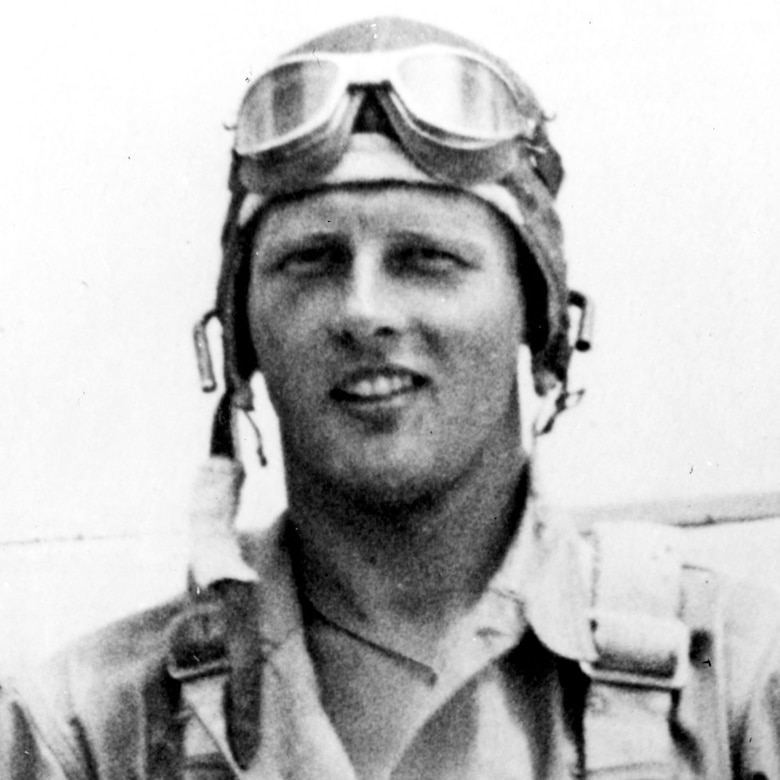 A pilot wears flight gear, a helmet and goggles.