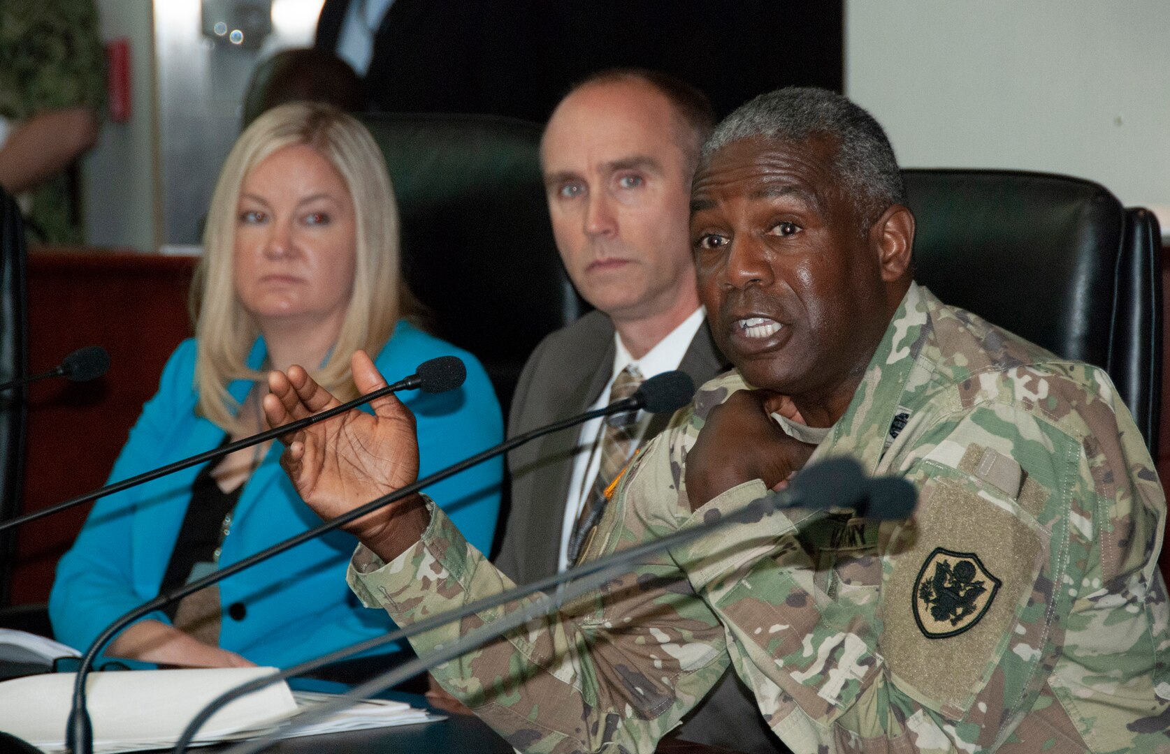 DLA Director Army Lt. Gen. Darrell Williams speaks into a microphone behind a table with other DLA leaders looking on