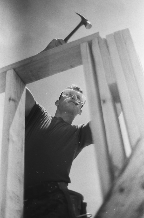 U.S. Marine Corps Lance Cpl. Logan Cayce, a combat engineer with Company C, 6th Engineer Support Battalion, 4th Marine Logistics Group, Marine Forces Reserve, nails the top of support structures together during the Innovative Readiness Training Camp Kamassa, near Crystal Springs, Miss., April 22. 2019. The purpose of the Department of Defense’s IRT program is to support the community by pairing military members with civil projects that benefit the community, and enables Marine Reserve units to increase their efficiency and performance. (U.S. Marine Corps 35mm film photo by Cpl. Niles Lee)