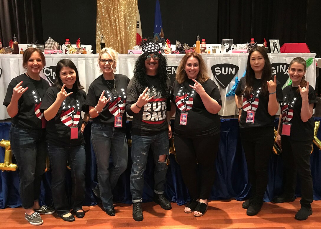 Cindy Wilsbach (center-left), spouse of Lt. Gen. Kenneth Wilsbach, Seventh Air Force commander poses with military spouses prior to the start of “Rocking the ROK,” an event honoring the service and sacrifice of military spouses at Osan Air Base, republic of Korea April 27. The evening’s celebration included some of the more traditional aspects of the Dining-in but substituted the mess dress uniforms, plated meal and formal centerpieces for a more upbeat theme. (Courtesy Photo)