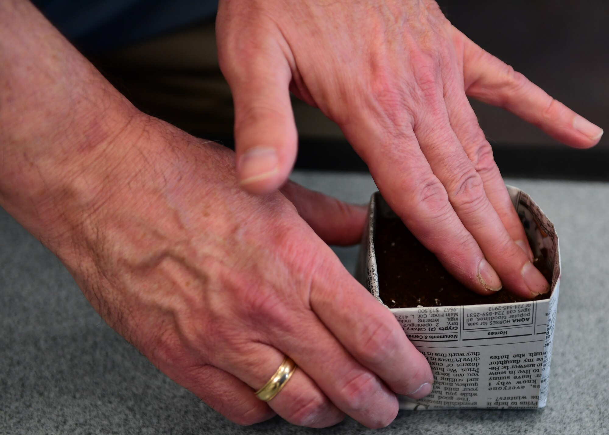 Robert Clifford, 911th Mission Support Group civil engineer, pats soil down at the Pittsburgh International Airport Air Reserve Station, Pennsylvania, May 2, 2019. The attendees had the opportunity to take soil and seeds to put in their newspaper pots to grow at home. (U.S. Air Force Photo by Senior Airman Grace Thomson)