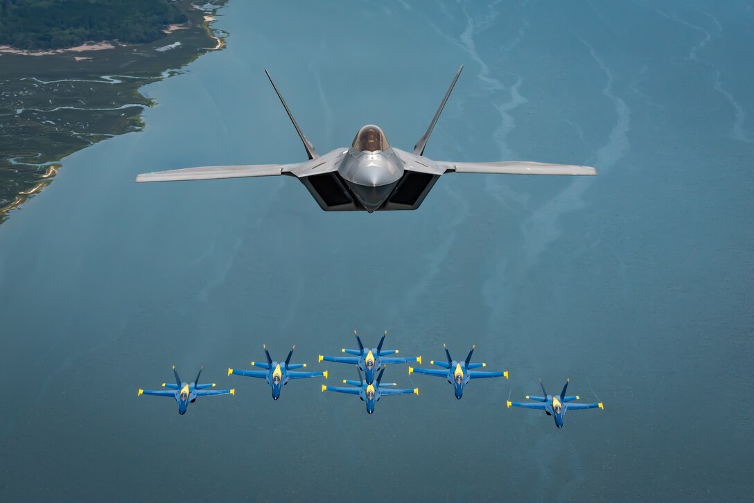 The F-22 Demo Team commander, flies above the U.S. Navy Blue Angels' iconic diamond formation
