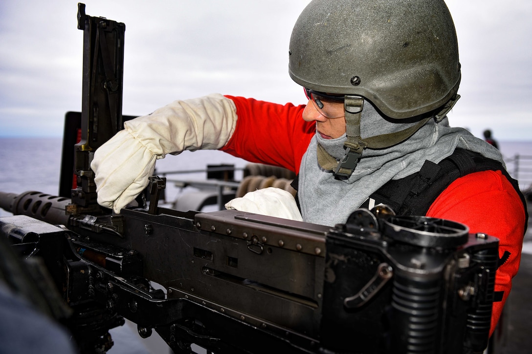 A sailor operates on a machine gun.