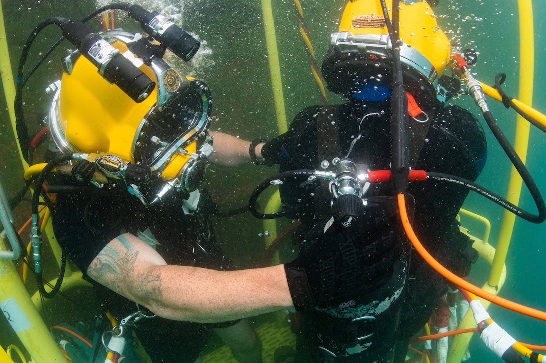 A diver adjusts the gas mix for another diver.