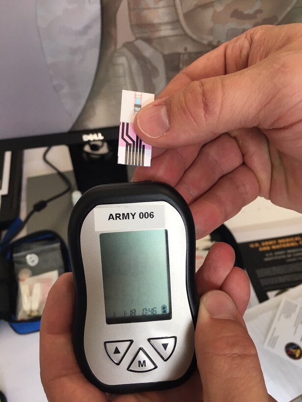 A man’s hands hold a small electronic medical device and a disposable chip.