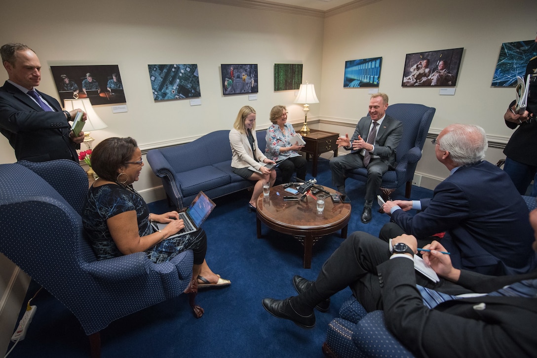 Acting Defense Secretary Patrick M. Shanahan sits in a chair surrounded by a small group of people.