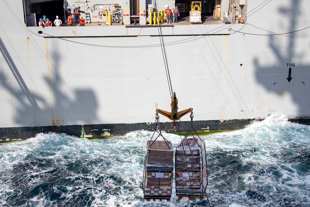 A ship sends supplies to another ship over the ocean.