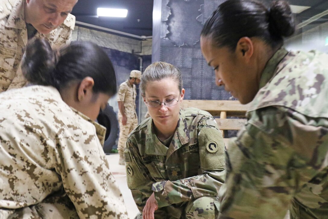 Service members look down to watch a demonstration.