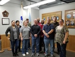 10 associates gather for a photo in front of two flags