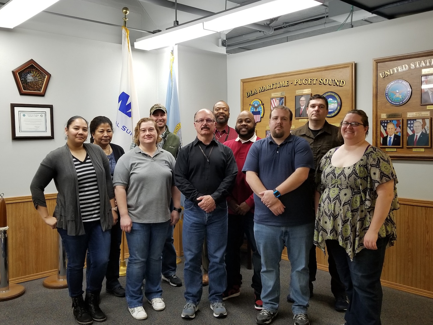 10 associates gather for a photo in front of two flags