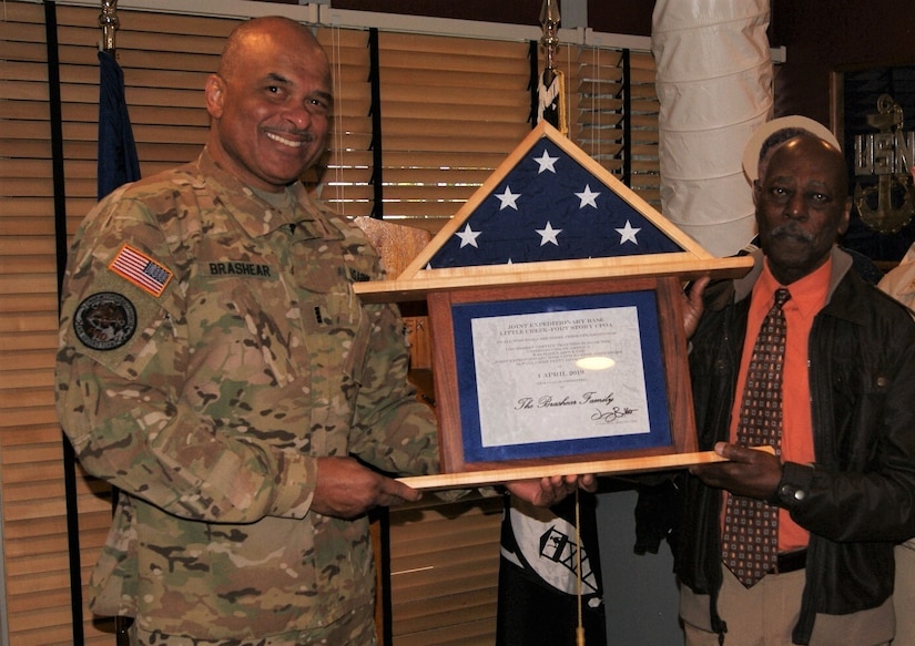 (Left to right) Chief Warrant Officer 4 Phillip Brashear and his uncle Randy Pritchett receive the American flag that was flown in honor of Brashear's late father Master Chief Boatswain's Mate Carl Maxie Brashear, at the flag-raising ceremony, at Joint Expeditionary Base Little Creek-Fort Story, Virginia, April 1, 2019.  Carl Brashear was a pioneer in the United States Navy, overcoming numerous barriers, to become the first African-American master diver and master chief.
