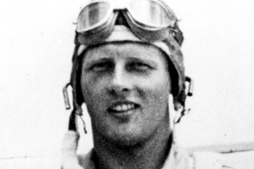 A pilot wears flight gear, a helmet and goggles.