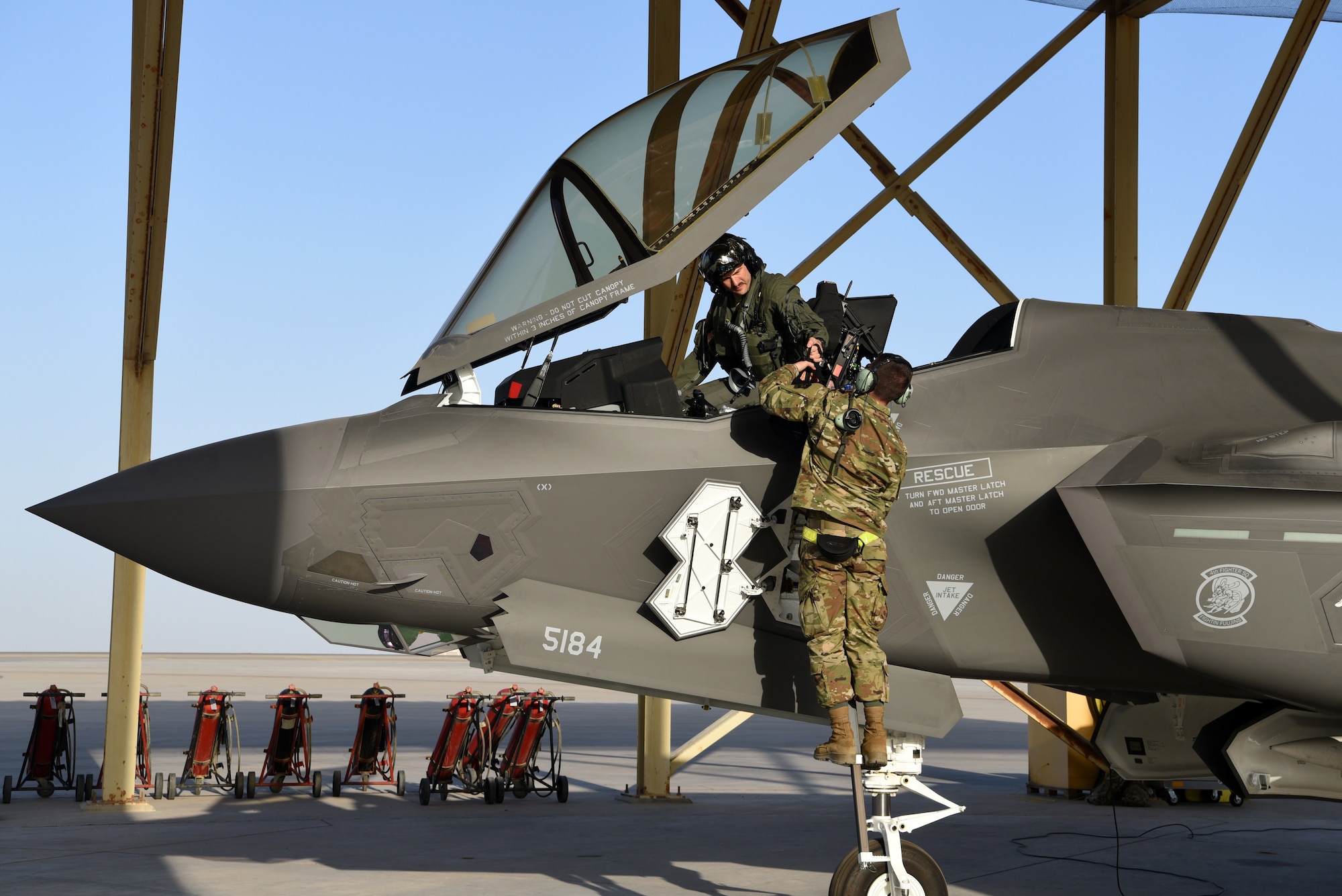 An F-35A Lightning II pilot assigned to the 4th Expeditionary Fighter Squadron passes gear to a 380th Expeditionary Aircraft Maintenance Squadron crew chief after running system checks on the aircraft April 26, 2019, Al Dhafra Air Base, United Arab Emirates.