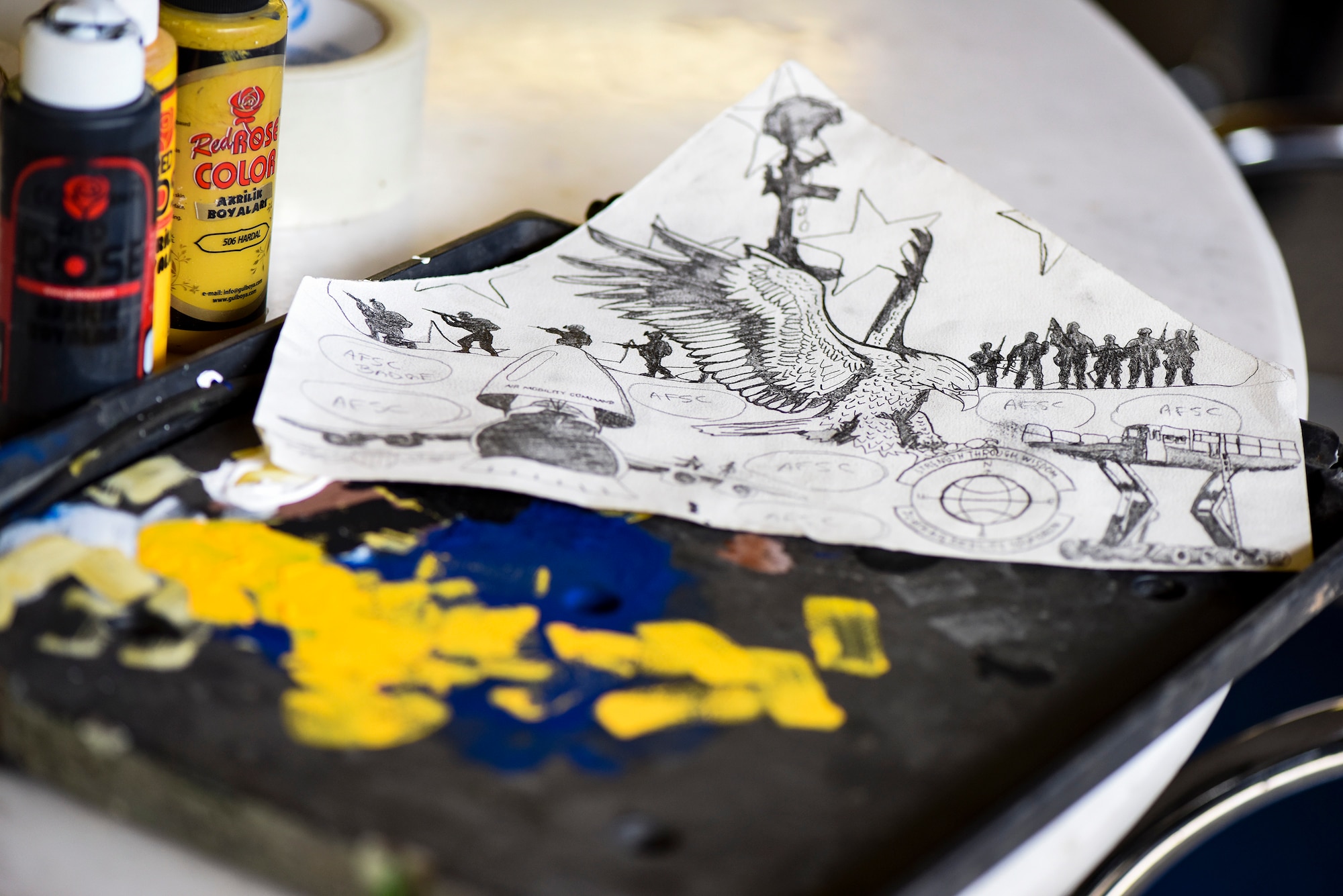 A drawing and paint supplies rest on a table in the 728th Aircraft Mobility Squadron’s heritage room Feb. 1, 2019, at Incirlik Air Base, Turkey. The 728th AMS selected Airman First Class Amber Branch, 728th AMS passenger services agent, to create a mural encompassing the unit’s mission. (U.S. Air Force photo by Staff Sgt. Ceaira Tinsley)