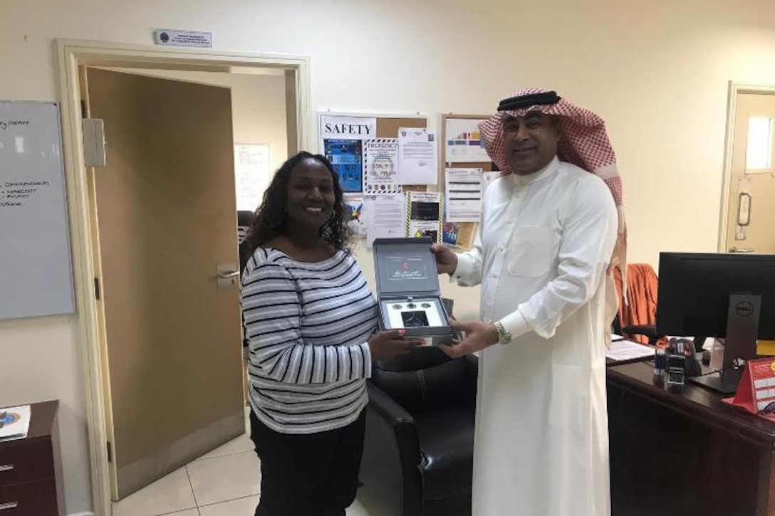 Shireen Washington, a disposition service representative for DLA Disposition Services in Bahrain, accepts replicas of historic items from Mohammed Ebrahim, a supervisor from the local Red Crescent Society, offered in appreciation for the furniture and other items provided to help the charity serve those in need.