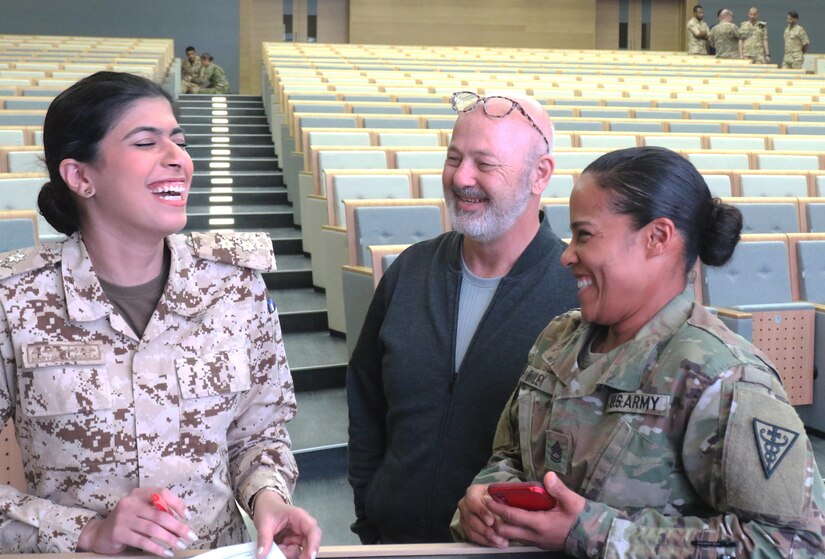 1st Lt. Maryam Abdulla, a doctor in the Bahrain Defence Force, and U.S. Army Sgt. 1st Class Misbah Bailey, 8th Medical Brigade, share a laugh while preparing a nine line at the Crown Prince Center of Training and Medical Research in Bahrain, April 16, 2019.