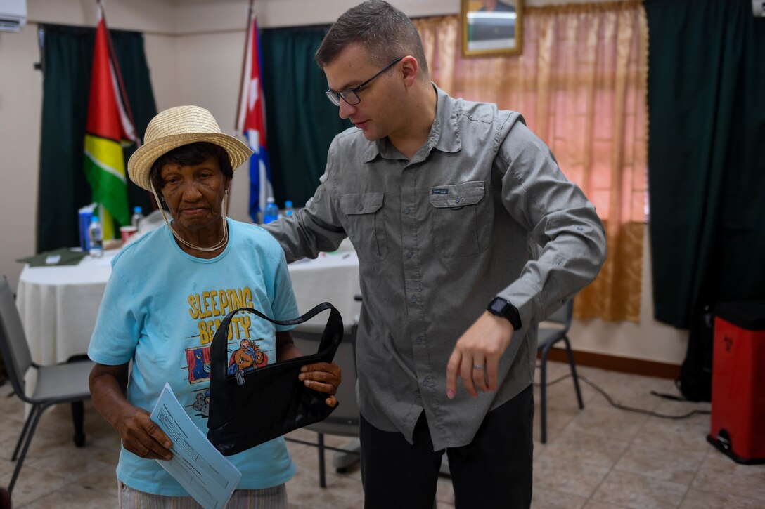 U.S. Air Force Maj. Andrew Lewis, ophthalmologist from Joint Base San Antonio-Lackland, Texas, guides a Guyanese patient to the next examine station during New Horizons 2019, Port Mourant, Guyana, May 3, 2019.