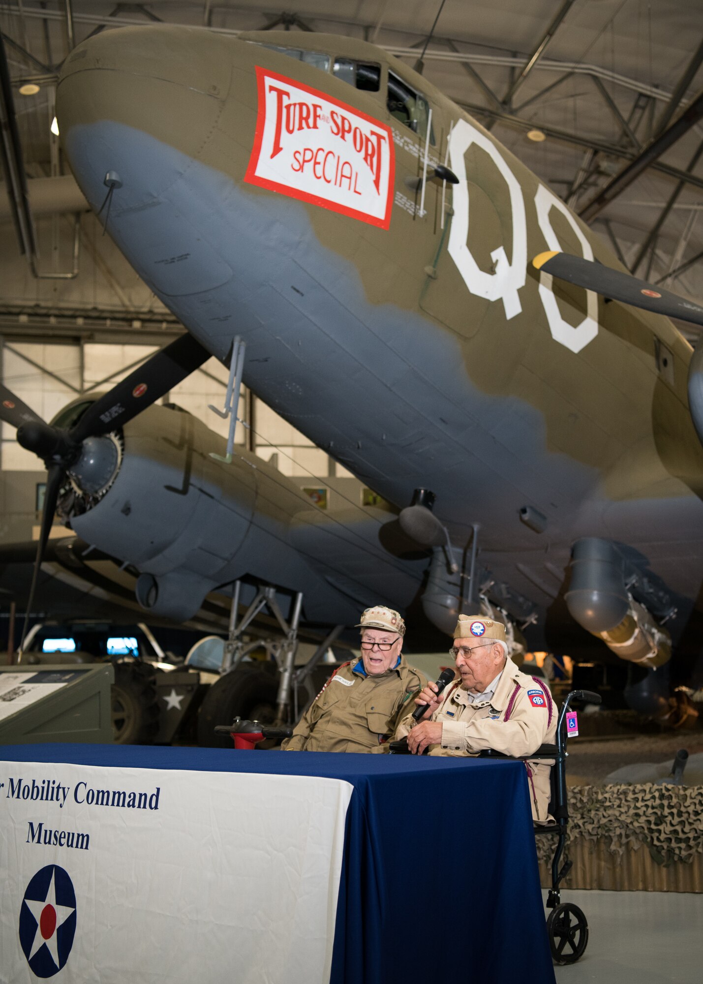 George A. Shenkle and Joseph Morettini, World War II veterans, speak to a crowd of spectators at the D-Day 75th Anniversary Commemoration May 4, 2019, at the Air Mobility Command Museum on Dover Air Force Base, Del. The Douglas C-47 Skytrain behind them is the very aircraft the two men parachuted from during the invasion of Normandy. (U.S. Air Force Photo by Mauricio Campino)
