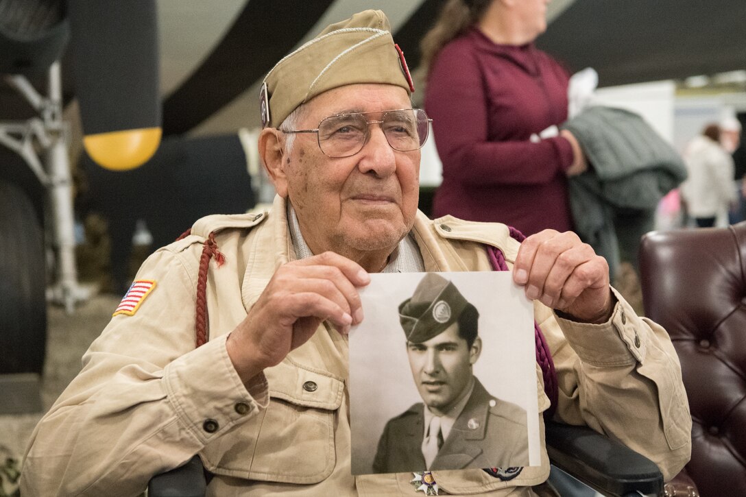 Joseph Morettini, World War II veteran, holds up his official Army photo from 1944 at the D-Day 75th Anniversary Commemoration May 4, 2019, at the Air Mobility Command Museum on Dover Air Force Base, Del. Morettini served with Easy Company, 508th Parachute Infantry Regiment, 82nd Airborne Division. (U.S. Air Force Photo by Mauricio Campino)