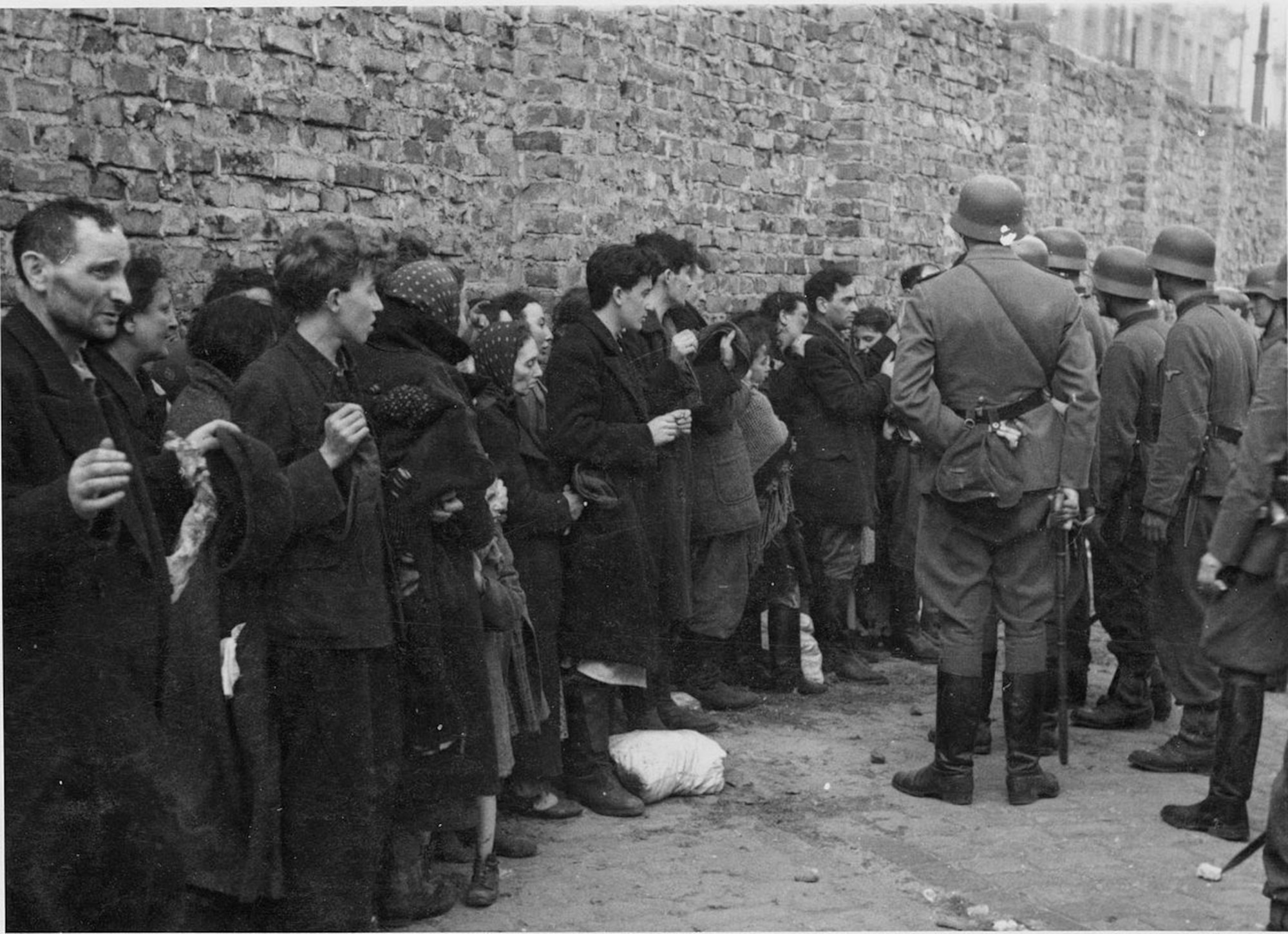 Captured Jews are searched for weapons and interrogated beside the ghetto wall before being sent to the Umschlagplatz, the Warsaw ghetto square where Jews were rounded up and organized for deportation to Treblinka. (Courtesy Photo)