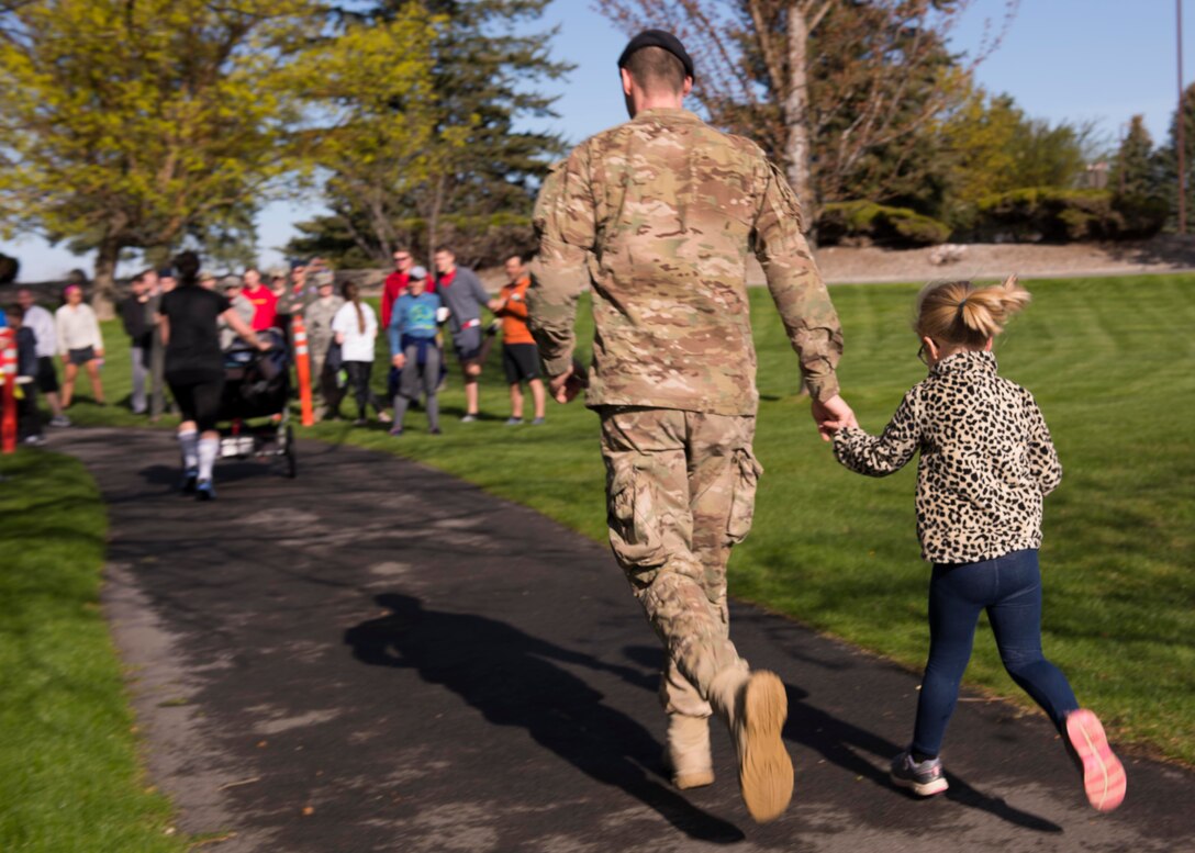 U.S. Air Force Maj. Joseph Schneider, 92nd Security Forces Squadron commander, runs to the finish line with his daughter during the commemorative Shell 77 5K Run at Fairchild Air Force Base, Washington, May 3, 2019. Ever since the crash that claimed the lives of three Airmen in 2013, Fairchild holds the run to honor the fallen flyers and stress the importance of remembering those that gave their lives for their country. (U.S. Air Force photo by Senior Airman Ryan Lackey)