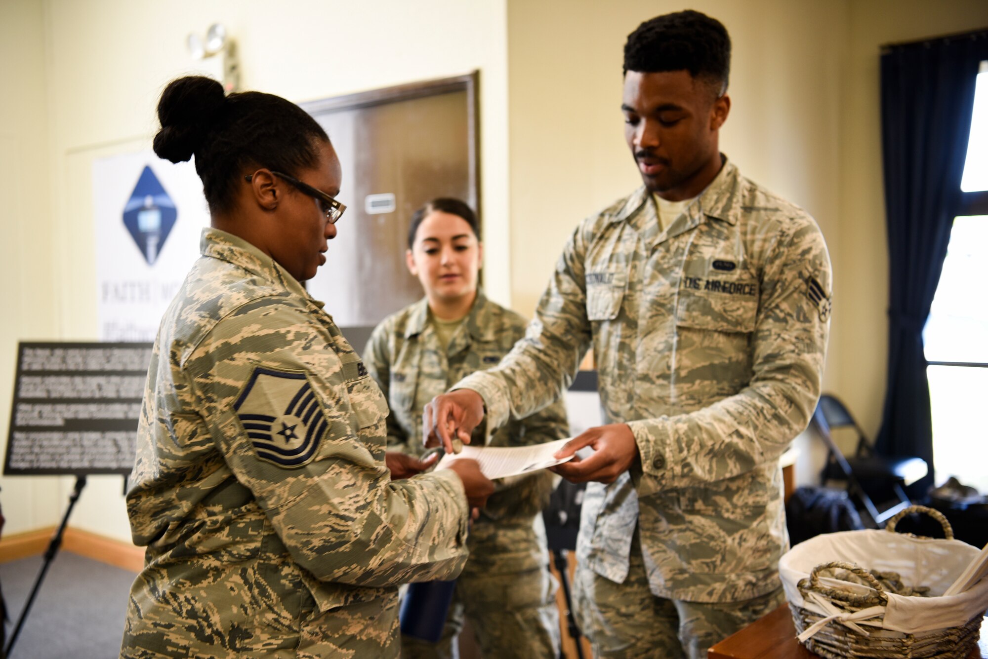 (Right) Senior Airman Jayln McDonald, 8th Communications Squadron base equipment control office technician, hands MSgt Deanna Beasley, 8th Inspector General Enterprise Management System manager, a pebble and a biographical card on a Holocaust victim prior to a remembrance ceremony May 2, 2019 on Kunsan Air Base, Republic of Korea. The ceremony is part of the national Days of Remembrance observance established by Congress to commemorate the Holocaust. This year, it is observed from April 28 through May 5. (U.S. Air Force photo by Capt. Remoshay Nelson)