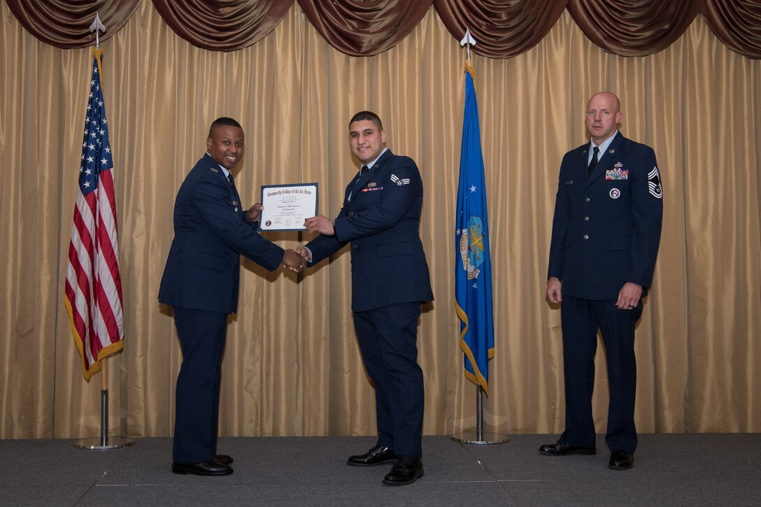 Senior Airman Pablo A. Altiery, 88th Aerial Port Squadron air transportation specialist, 514th Air Mobility Wing, Joint Base McGuire-Dix-Lakehurst, N.J., is presented with his Community College of the Air Force Associates Degree by Col. Adrian R. Byers, 514th AMW vice commander, May 3, 2019.