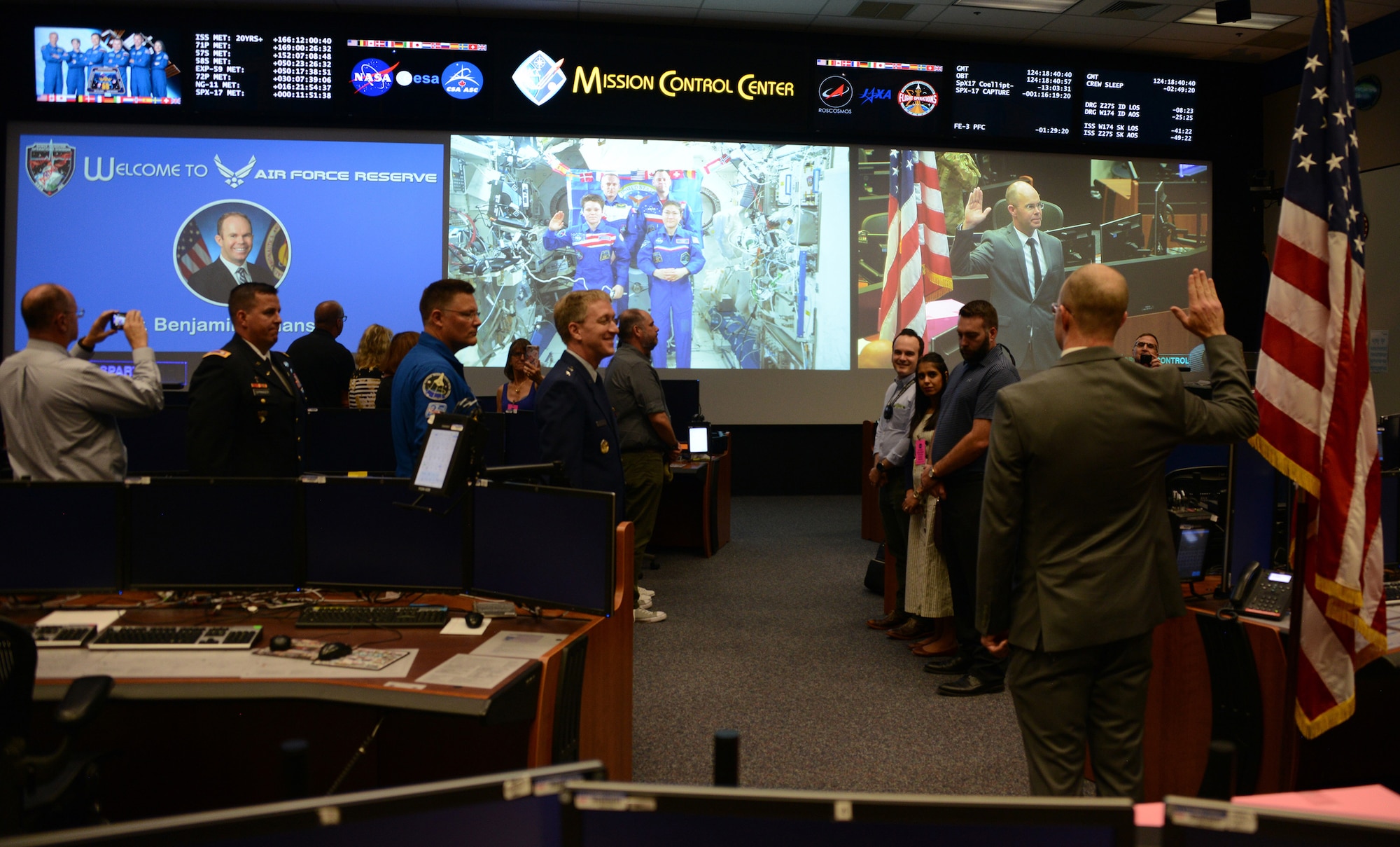 Dr. Benjamin Johansen, stands with his right hand raised as he is administered the commissioning oath by Army Lt. Col. Anne McClain, an astronaut on the International Space Station, 210 miles above earth. Johansen is joining the Air Force Reserve as a flight surgeon and will wear the rank of a captain, but as a civilian he is a flight surgeon with NASA and is assigned as one of two flight surgeons for McClain. (Air Force photo/Master Sgt. Chance Babin)