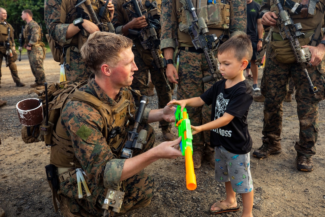A Reconnaissance Team Leader Course Instructor observes Haven Tablada’s toy rifle after a raid demonstration, Marine Corps Training Area Bellows, May 4, 2019. The Marine Reconnaissance Foundation conducted their annual Gold Star Family retreat, allowing the families to observe a raid to get a better picture of what their father, husband or son did when they served in the U.S. Marine Corps.