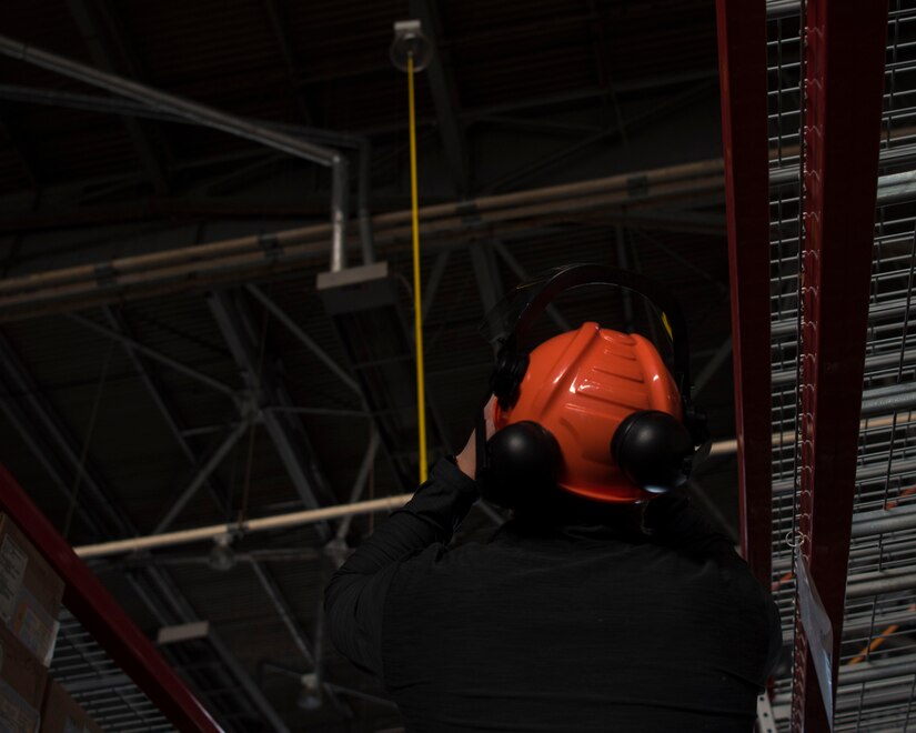 Christopher Falkowski, facilities engineer with Engineering Services & Support Branch of the Materials and Manufacturing Directorate, observes a new light bulb being lifted into its socket at Joint Base Langley- Eustis, Virginia, April 30, 2019. Falkowski was sent in from Wright-Patterson Air Force Base, Ohio, to help aid in changing these light fixtures. (U.S. Air Force photo by Airman 1st Class Marcus M. Bullock)