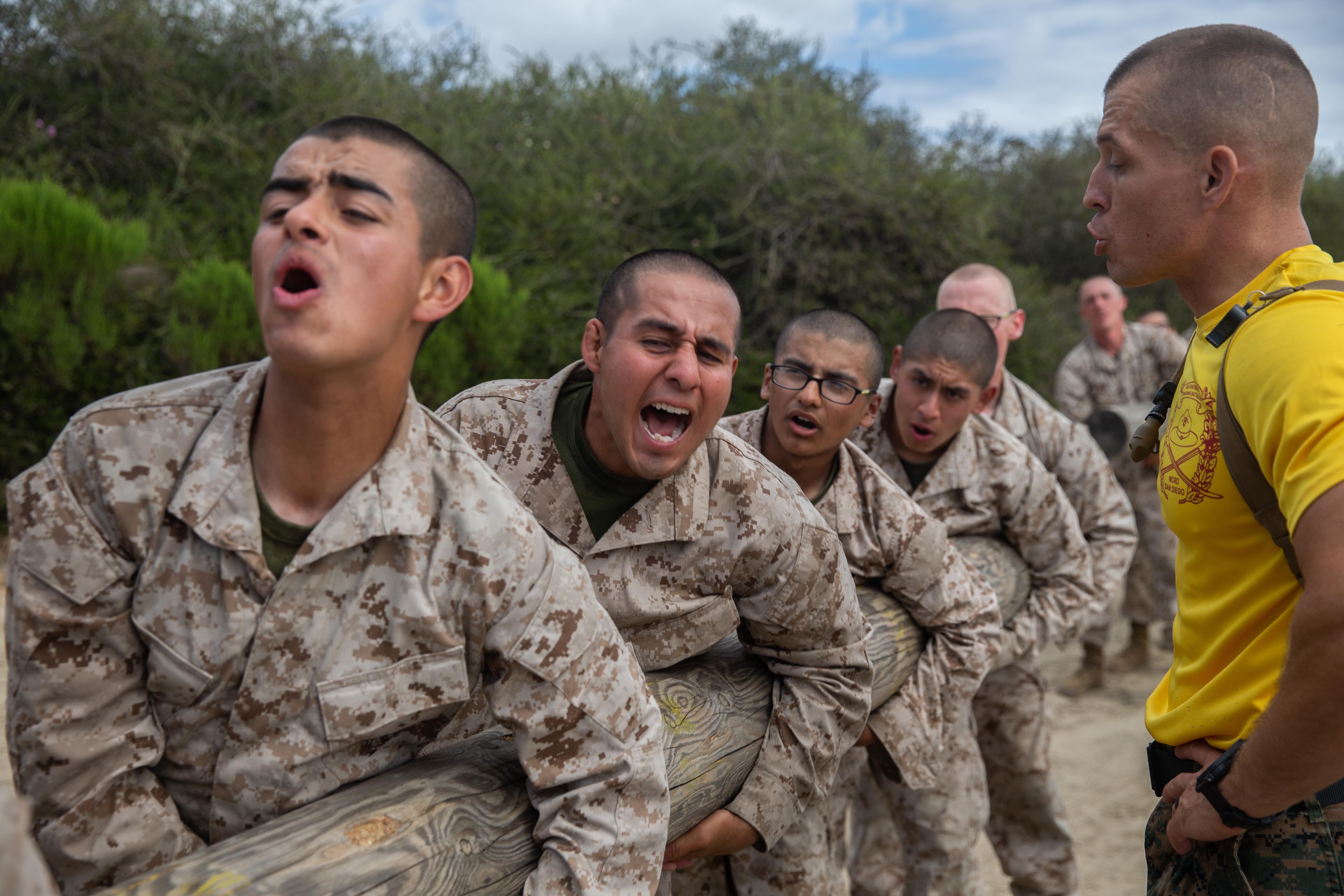 Marine Corps recruits perform side curls with a log at Marine Corps