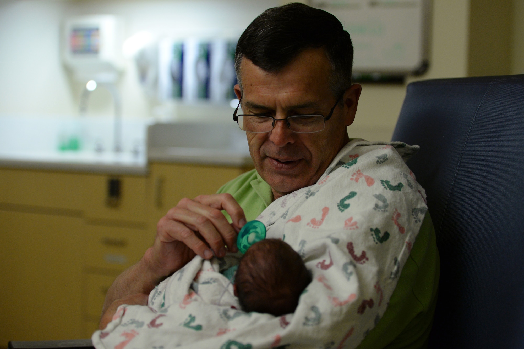 David Young, 60, Air Mobility Command current operations air mobility analyst and retired Air Force pilot, offers a pacifier to a premature baby in the Neonatal Intensive Care Unit at Mercy Hospital in St. Louis, April 19, 2019. Young participates in a “cuddler program” organized by the hospital to boost the babies’ brain development and increase their overall survival rate. (U.S. Air Force photo by Airman 1st Class Miranda Simpson)