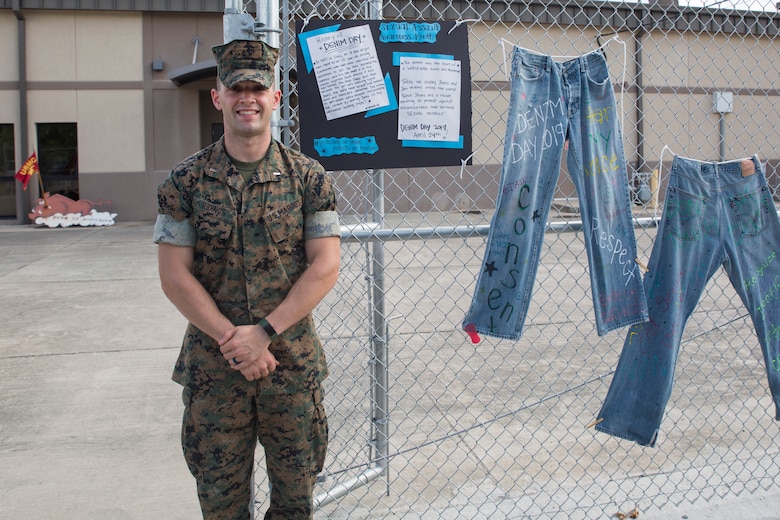 1st Lt. Jacob Ridings stands in front of a Denim Day display that was set up for a Sexual Assault Awareness Month campaign aboard Marine Corps Air Station Beaufort, May 1. Denim Day began nearly 20 years ago after a rapist’s conviction was overturned by the Italian Supreme Court because the justices felt that since the young woman was wearing tight jeans, she must have assisted the rapist in removing them. The next day, the women in Italian Parliament came to work wearing denim, and now annually one Wednesday in April is honored as Denim Day. This was one of several awareness displays set up around Marine Wing Support Detachment 273. Ridings is a SAPR advocate with MWSD-273. (U.S. Marine Corps photo by Cpl. Ashley Phillips)