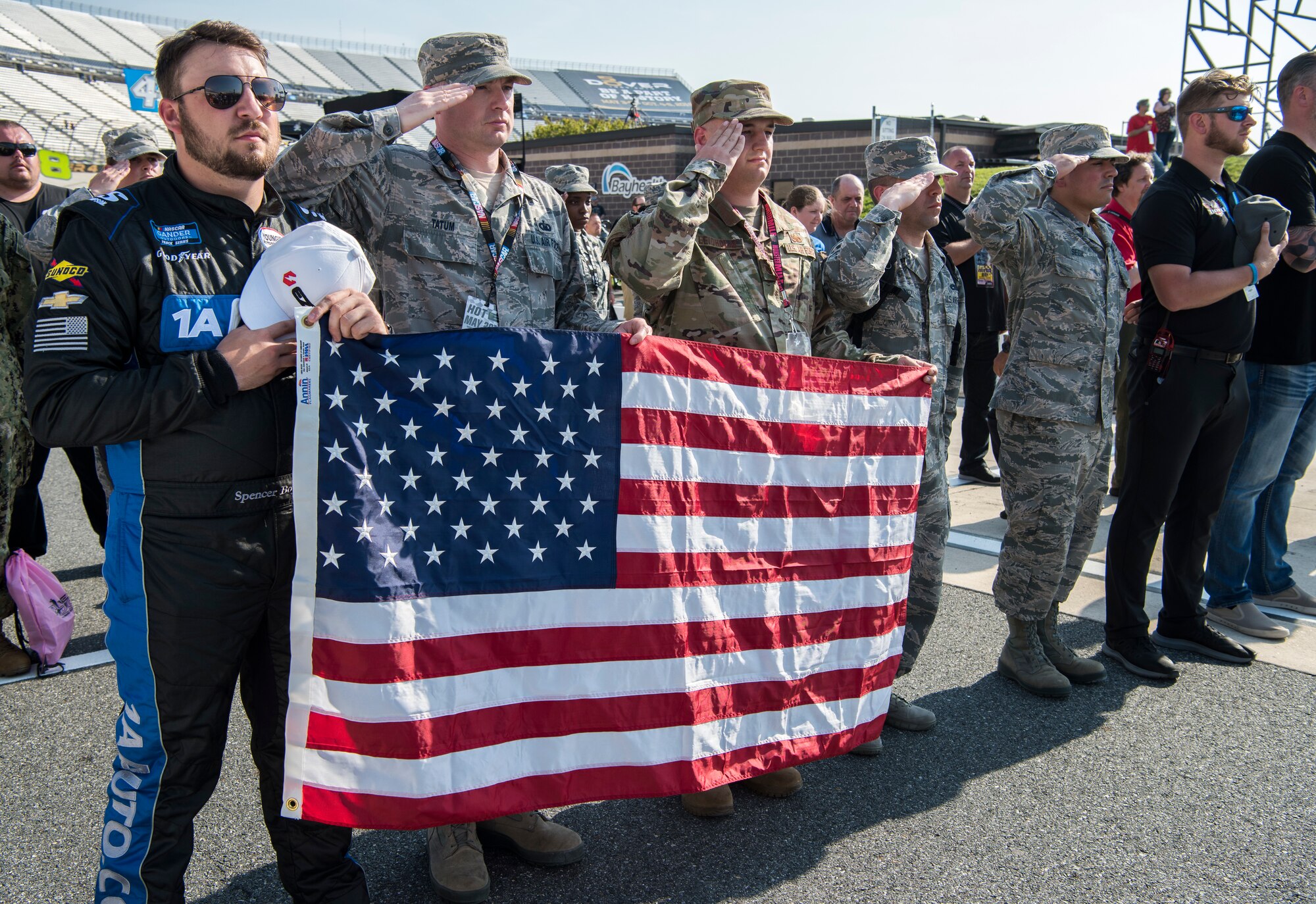 Honorary pit crew members, NASCAR drivers and pit crew members salute during the singing of the national anthem before the start of the JEGS 200 race May 3, 2019, at Dover International Speedway in Dover, Del. NASCAR teams partner with Dover Air Force Base to offer Dover service members the opportunity to participate as a team member during the race. Each race, roughly 35 service members attend as honorary pit crew members. (U.S. Air Force photo by Senior Airman Christopher Quail)